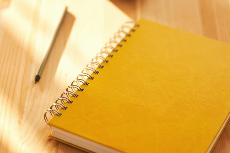 Osoba zapisující si nápady do zápisníku u stolu